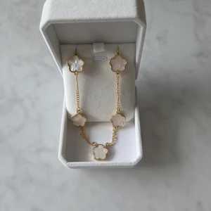 Halsband med vita blommor - Superfint halsband med blommor i vit som är väldigt fin den är ny