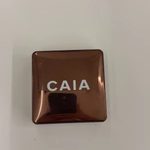 CAIA glow bronzer i Gold Coast - Glow bronzer från CAIA. Pudret har en varm brun nyans som ger en solkysst look och är perfekt för contouring eller att addera glow till ansiktet.