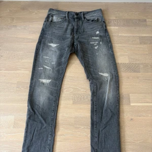 Grå slitna jeans från Herrlicher slim fit - Säljer ett par grå jeans från Herrlicher med snygga slitningar och tvättad look. Dessa trendiga jeansen har en perfekt slimmad passform!