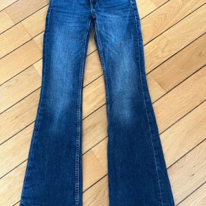 Bootcut jeans från Lager 157, mörkblå - Bootcut jeans från Lager 157 i en snygg mörkblå tvätt. Modellen är lågmidjad med klassisk femficksdesign och lätt slitna detaljer. Perfekta för dig som gillar en retro vibe och vill ha ett par jeans med lite vidare ben nertill.
