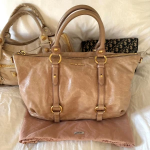 Vitello Shine Cammeo väska Miu Miu - 🤍Säljer billigare via min vinted @juliavallberg pga avgifter 🤍Shine Bauletto, färg Cammeo, en mjuk beige ton med varm underton. Väskan är i väldigt fint skick och kommer med original dustbag och äkthetskort (se bild). Väldigt lite använd. Endast en lite slitage som knappt syns. Ren invändigt och perfekta gulddetaljer. Klassisk Miu Miu-modell som inte längre säljs i butik🤍  Modell: Vitello Shine Bauletto Färg: Cammeo Artikelnummer: RN0621 Gruppkod: US0 F0770 00 Produktionskod: P101 2010 27927 A