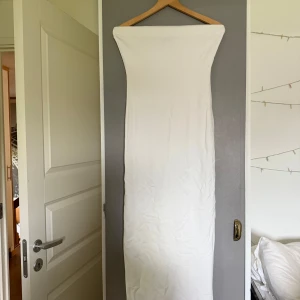 Vit axelbandslös långklänning NA-KD - Vit bandlös klänning med slits baktill. Storlek M. Endast testat inomhus