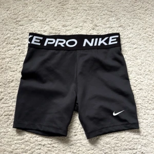 Svarta Nike Pro träningsshorts - Säljer dessa Svarta Nike Pro Dri-Fit. Tight passform och tillverkade i ett stretchigt, fukttransporterande material som passar perfekt för träning. Storleken är XL men passar mig som brukar ha storlek S, då materialet är jättestretchigt!!🩷bilder går att lösa med dom på