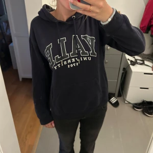 Mörkblå Yale hoodie med tryck - Säljer en mörkblå hoodie med stor vit logga och text framtill. Tröjan har huva med snörning och en klassisk känguruficka. Perfekt för dig som gillar college-stil och vill ha en skön och avslappnad look.