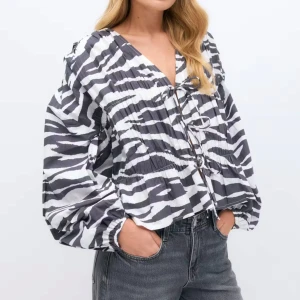 Zebramönstrad blus från Gina Tricot - Säljer en luftig zebramönstrad blus från Gina Tricot med svartvita ränder. Blusen har v-ringning, snörning framtill och ballongärmar. Perfekt för dig som vill sticka ut med en trendig och cool look. Materialet är lätt och känns skönt mot huden.