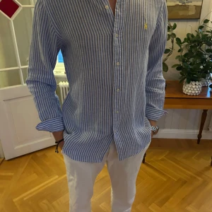 Ralph Lauren Linneskjorta - Snygg blå och vit randig skjorta från Polo Ralph Lauren i custom fit. Härlig linneskjorta, perfekt för varmare dagar. Modell är 183cm & 75kg. Bara att skriva om ni undrar något! Har även massa annat på min profil! Kika!