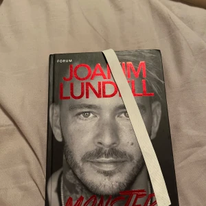 Monster - En bok med svart omslag och röd text, skriven av Joakim Lundell. Perfekt för dig som gillar starka berättelser och vill läsa något som sticker ut. Passar ungdomar och unga vuxna som söker något annorlunda och spännande. Limmat fast ett band ist för att göra hundöron