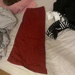 Mörkröd långkjol i mjukt tyg - Säljer en snygg mörkröd långkjol med rak passform. Kjolen har en enkel och clean design utan synliga detaljer, perfekt att styla med både sneakers och boots. Tyget känns mjukt och flowy, vilket gör den superbekväm att bära hela dagen.