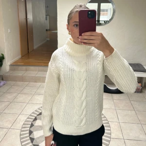 Vit polotröja med flätmönster från Vila - Säljer en superfin vit polotröja från Vila i storlek XS. Tröjan är stickad med grovt flätmönster framtill och har höga muddar samt en rejäl polokrage. Perfekt för kyliga dagar och riktigt mysig att bära. Knappt använd!