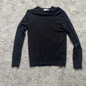 Svart merinoulltröja från Selected Homme - En stilren svart tröja från Selected Homme i mjuk merinoull. Klassisk rund halsringning och långa ärmar, perfekt för lager-på-lager. Enkel och clean design som funkar till det mesta. Snygg passform och ribbade muddar vid ärmslut och nederkant. Skriv vid frågor eller funderingar 