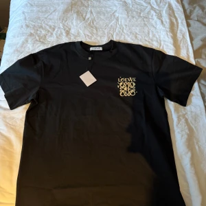 Svart Loewe t-shirt  - Svart t-shirt från Loewe i 100% bomull med snygg Loewe-logga tryckt på bröstet. Helt ny och oanvänd. Storlek L, något större passform! 