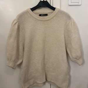 Beige stickad tröja från Gina Tricot - Supermysig beige stickad tröja från Gina Tricot med puffiga trekvartsärmar och bred ribbad kant vid hals, ärmslut och nederkant. Perfekt för lager-på-lager och ger en chill men ändå trendig vibe till din outfit.
