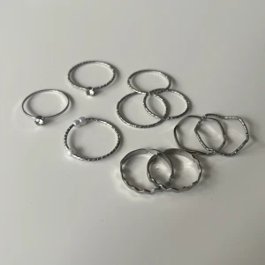 Snygga silverfärgade ringar i set (rostfritt) - Ett set med flera tunna ringar i silverfärg, vissa med små pärlor och stenar, andra med vågig eller sexkantig form. Perfekta att mixa och matcha för en personlig stil. Passar både till fingrar och som midi-ringar. Köpta utomlands