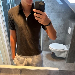  pikétröja med half zip - Snygg brunaktig pikétröja med kort ärm och modern half zip-dragkedja framtill. Tröjan har klassisk krage och är tillverkad i ett mjukt material som känns skönt mot huden. Perfekt för dig som vill ha en stilren och enkel look. Passar även xs