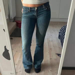Blå Levis jeans - Säljer ett par snygga blå Levis jeans i bra skick ( förutom den spruckna lappen som syns på bilden ). De är lågmidjade och bootcut. Inrebenslängden är 80cm och midjemått 38cm🥰 använd gärna köp nu💕( vid snabb affär är jag öppen för prisförslag )