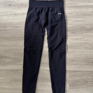 Svarta leggings från ICANIWILL - Svarta leggings från ICANIWILL med hög midja och bred ribbad linning. Tight passform och stretchigt material som passar perfekt till träning eller chill. Diskret logga framtill på höften. Snygga och bekväma för en aktiv livsstil. Storlek M. Säljes då de var för stora på mig!