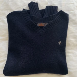 Marinblå stickad tröja från Morris - Köp flera plagg för rea! • Marinblå stickad tröja från Morris med v-ringad hals och ribbade muddar. Tröjan har en liten broderad logga på bröstet och är perfekt för kyliga dagar. Klassisk och stilren design som funkar till det mesta. I toppskick, använt få gånger!