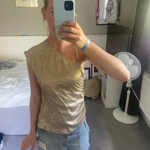 Guldig one shoulder topp - Snygg glittrig guldig topp aldrig använd från hm 