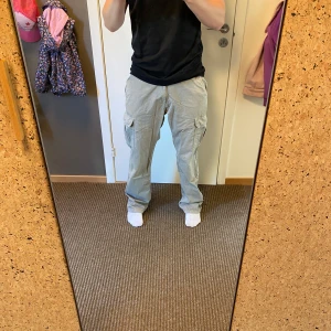 Beiga cargopants med raka ben - Säljer ett par beiga cargopants med raka ben och stora fickor på sidorna. Byxorna har en avslappnad passform och är perfekta för en chill och streetig stil. Tillverkade i bomull för skön känsla hela dagen.