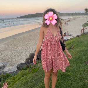 Röd paisleymönstrad sommarklänning - Supersöt röd kortklänning med paisleymönster och v-ringning. Klänningen är ärmlös med tunna axelband och har öppen rygg. Passar mig som är strl S