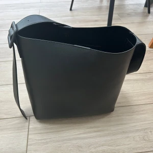 Stor handväska  - Säljer min svarta handväska från NA-KD, är i bra skick och har inga tecken på skador. Knäpps med knapp och har en innerficka💞