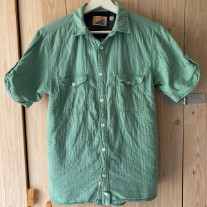 Valient skjorta - Turkos kortärmad skjorta i perfekt skick. 100% bomull och tvätt 40 grader enligt etikett. Upphämtning i Stockholm fungerar.