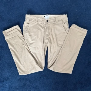 Beige chinos från Win Win, storlek M - Snygga beige chinos från Win Win i klassisk rak modell. Byxorna är storlek M och sparsamt använda. Sitter bra på mig som är 180cm och 75kg. Tveka inte att skriva vid funderingar 💯