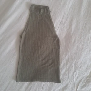 Ribbad grön topp ärmlös - Säljer en stilren ribbad topp i grönt. Toppen är ärmlös och har en tight passform som framhäver axlarna. Perfekt att styla med jeans eller kjol för en clean look.