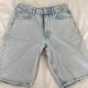 Ljusblå jorts - Säljer ett par EXTREMT EFTERTRAKTADE ljusblå jeansshorts /jorts med klassisk femficksdesign och bälteshällor. Modellen är loose fit och har en rak, lite längre passform. Perfekta för sommardagar och ger en avslappnad vibe. Dragkedja och knapp framtill. 