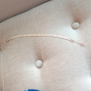 Guldigt armband med fiskbenslänk - Snyggt armband i guldig färg med fiskbenslänk som ger en stilren och trendig look. Perfekt accessoar för att lyfta din outfit med lite extra bling. Lätt att matcha med andra smycken och har ett smidigt spänne.