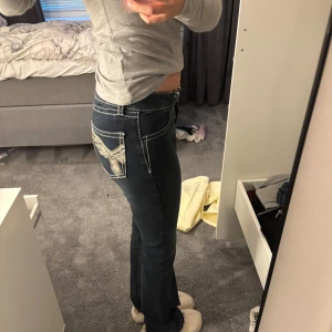 Mörkblå bootcut jeans med broderi - Säljer ett par mörkblå jeans med bootcut passform, lågmidjade från gina. (jag har sprättat upp de längst nere vid benen så de är lite fransar av de då de var för korta för mig som är 167, passar nu jätte bra i längd!) de är använda kanske 1-2 gånger! (nypris 500)