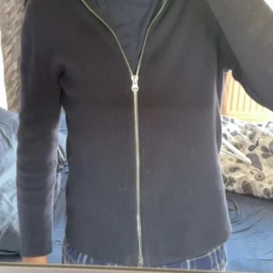 Svart ribbad cardigan jacka från Ljung - Svart ribbad cardigan jacka från Ljung by Marcus Larsson i storlek M. Jackan har hel dragkedja framtill, lång ärm och är tillverkad i mjuk bomullsblandning med elastan för extra stretch. Enkel och clean design som funkar till allt.