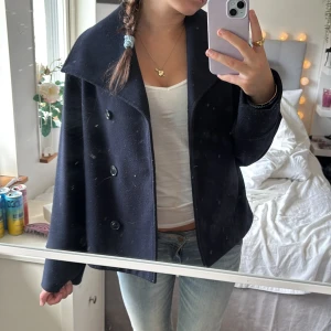 Mörkblå kappa med knappar - Snygg mörkblå kappa och dubbelknäppning framtill. Jackan ger en fin look och är tillverkad i ett tjockare ullmaterial som håller dig varm. Den är från Gina tricot. St  158-164 men passar även på mig som är storlek xs-s. Använd gärna köp nu