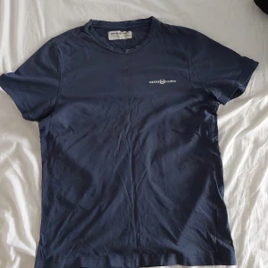 Mörkblå t-shirt från Henri Lloyd - Säljer en mörkblå t-shirt från Henri Lloyd med liten vit logga på bröstet. Klassisk rund hals och korta ärmar. Perfekt basic-plagg för garderoben.