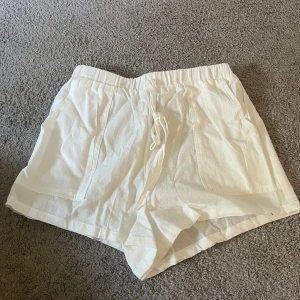 Vita linneshorts - Snygga och luftiga vita shorts i linne med elastisk midja. Perfekta för varma dagar och har två fickor framtill. Klassisk och enkel design som passar till det mesta.