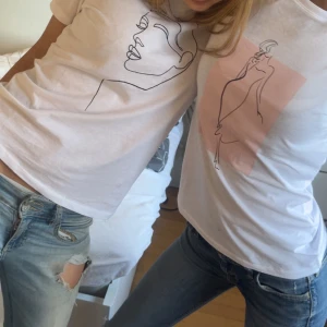 Vit t-shirt med minimalistiskt ansiktsmotiv - Vita t-shirts med tryck av minimalistiskt ansikte i svart linje och rosa bakgrund. Klassisk passform och rund halsringning. Perfekt för en stilren och modern look. Man får båda för priset❤️
