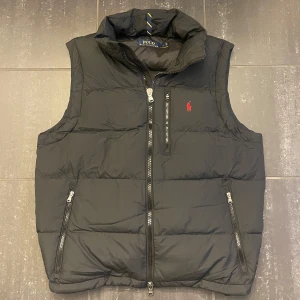 Svart dunväst från Polo Ralph Lauren - Tja, säljer min lillebrors Ralph Lauren väst då han vill köpa något nytt. Västen är i storlek M och är som nyskick. Kan tänka mig att gå ner i pris vid snabb affär och du har frågor är det bara att skriva👍