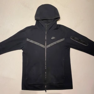 Nike tech fleece - Svart Nike tech fleece i bra skick. Enda defekten är en liten fläck och riv märke på ärmen som finns i sista bilden. Förutom det har den inga defekter alls. Säljer då jag inte använder den längre. Den passar både som S och M. 