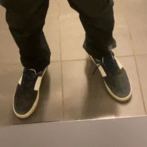 Svarta sneakers med vita detaljer - Säljer ett par svarta sneakers med vita sidor och vit sula. Skorna har snörning och en klassisk, sportig look som passar till många outfits. Rockrunners 