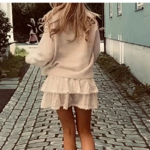 Vit kjol med spetsdetaljer - Säljer en söt vit kjol med volanger och spetsdetaljer. Perfekt för sommarens alla tillfällen. Kjolen har en kort längd och är gjord i ett lätt och luftigt material. KÖPT PÅ PLICK MEN PASSADE EJ!