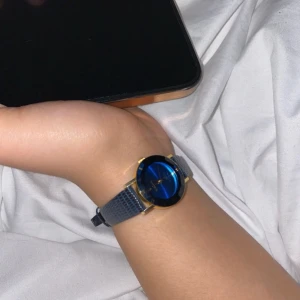 Vintage klocka  - Säljer en stilren klocka från Geneva med blå urtavla och blått skinnarmband. Klockan har guldiga detaljer runt urtavlan och romerska siffror. Perfekt accessoar för att lyfta din outfit.