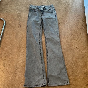 Ljusgrå bootcut jeans från Nelly - Säljer ett par ljusgrå jeans från Nelly med bootcut-passform och klassiska fem fickor. Jeansen har låg midja och dekorativa sömmar på bakfickorna. Perfekta för dig som gillar retrostil och vill ha ett par snygga jeans med lite utsvängda ben.
