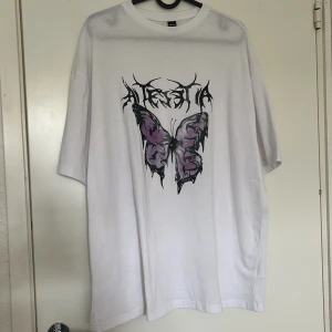 Vit oversized t-shirt med fjärilstryck från SHEIN - en vit väldigt oversized t-shirt från SHEIN med stort tryck av en lila och svart fjäril samt text på bröstet. aldrig använd🩷