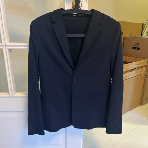 Mörkblå kostym från Zara Man - Säljer en stilren mörkblå kostym från Zara Man. Kavajen har klassisk passform med en knapp och raka fickor. Byxorna är raka med pressveck. Perfekt för skolavslutningen! Storlek 164 cm 