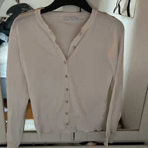 Vit kofta med knappar från Gina Tricot - Säljer en enkel och stilren vit kofta från primark. Koftan har långa ärmar, rund halsringning och knappar framtill. 