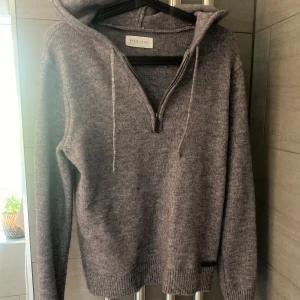 Grå stickad hoodie från Pier One - Mysig grå stickad hoodie från Pier One med dragkedja framtill och huva med snören. Perfekt för kyliga dagar och enkel att matcha med olika outfits. Ribbstickade muddar vid ärmslut och nederkant. Liknar merinoull, hör av er vid minsta fundering!!!