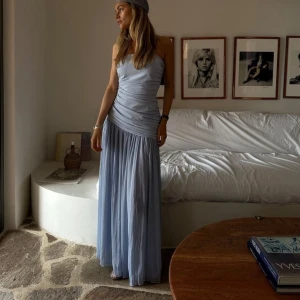 Ljusblå bandeau långklänning - Säljer en helt ny ljusblå axelbandslös långklänning med draperad överdel och plisserad kjol, med lapparna kvar. Slutsåld 🩵passar perfekt som balklänning!