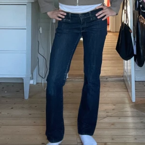 Mörkblå bootcut jeans från 7 For All Mankind - Säljer ett par mörkblå jeans från 7 For All Mankind med bootcut passform. Jeansen har klassiska fickor bak med dekorativa sömmar och låg midja. Perfekta till en avslappnad stil och passar till det mesta.
