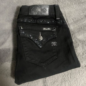 Miss me jeans  - Snygga svarta jeans från Miss Me med glittriga detaljer och broderier på fickorna. Mid-rise modell med silverfärgade knappar och dragkedja. Tillverkade i bomull med lite stretch för skön passform. Säljs då dom är för små!