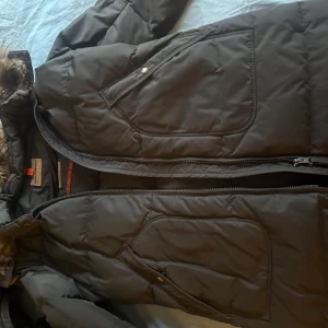 Svart dunjacka med fuskpäls från Parajumpers - Säljer en svart dunjacka från Parajumpers med stor huva och fuskpäls. Jackan har dragkedja framtill, stora fickor och quiltad design. Perfekt för kalla dagar och riktigt varm. ÄKTA PARAJUMPER JACKA  säljer för 1700 men pris kan diskuteras 